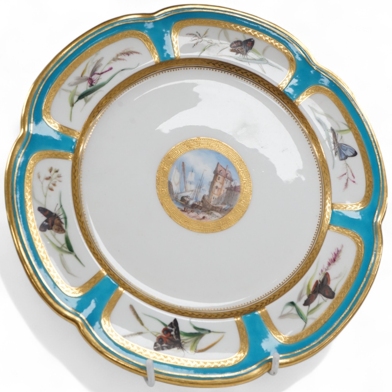 A Minton turquoise and gilt cabinet plate, decorated with butterflies and central continental harbour scene, 24cm diameter.